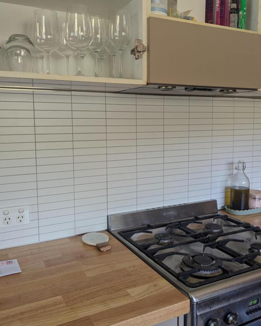 Kitchen backsplash with Matte White Kit Kat Stick on Composite Tiles, installed behind a stove and wooden countertop for a sleek look.