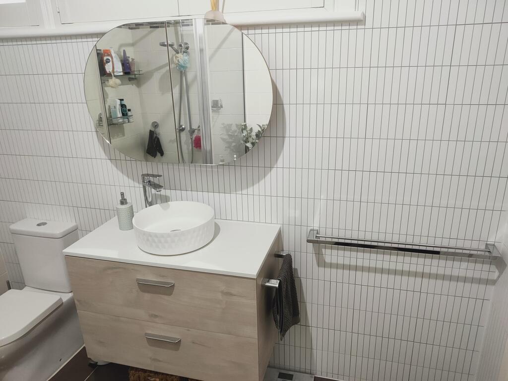 Bathroom interior featuring Matte White Kit Kat Stick on Composite Tiles, installed behind a vanity and mirror for a clean, modern look.