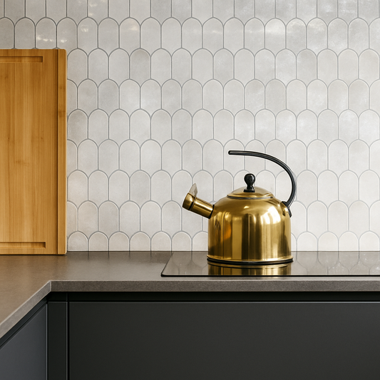 Gold kettle on a kitchen counter with a patterned tile backsplash