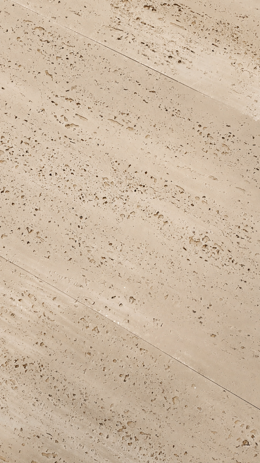 Beige travertine stone tile with natural porous texture and diagonal seams.