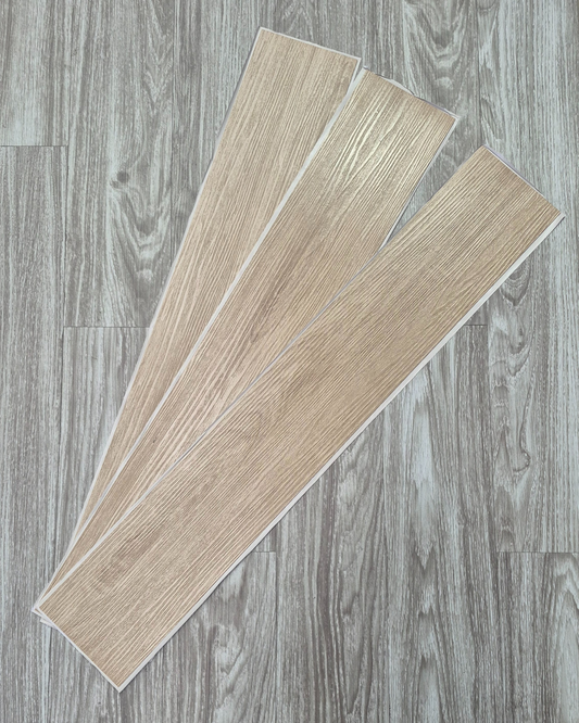 Two pieces of beige vinyl flooring on a gray wooden floor background