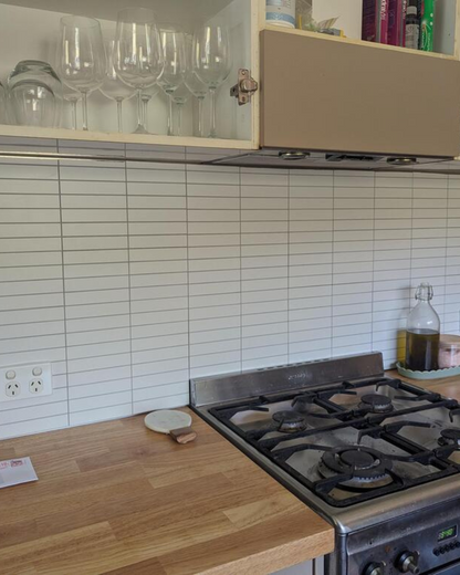 Kitchen backsplash with Matte White Kit Kat Stick on Composite Tiles, installed behind a stove and wooden countertop for a sleek look.