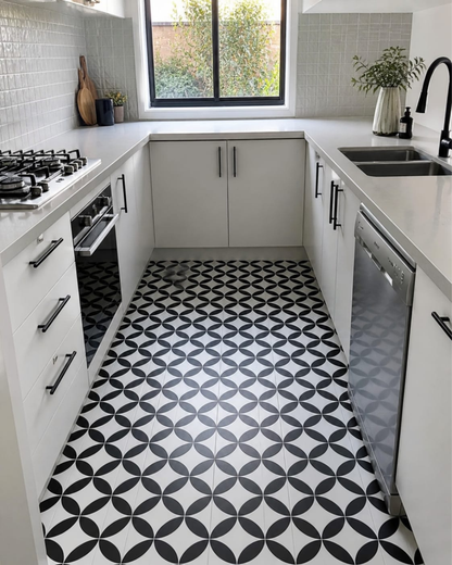 Modern kitchen with white cabinets, black and white patterned floor, and window view.