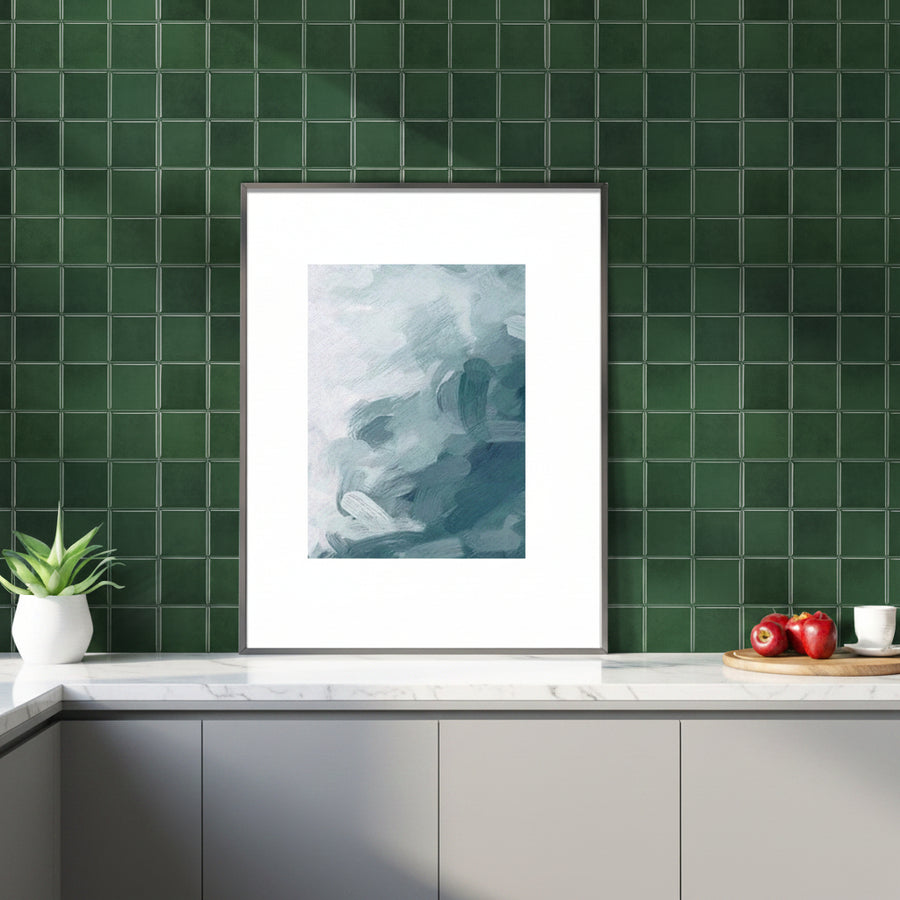 Framed abstract art on a green tiled wall above a wooden cabinet.