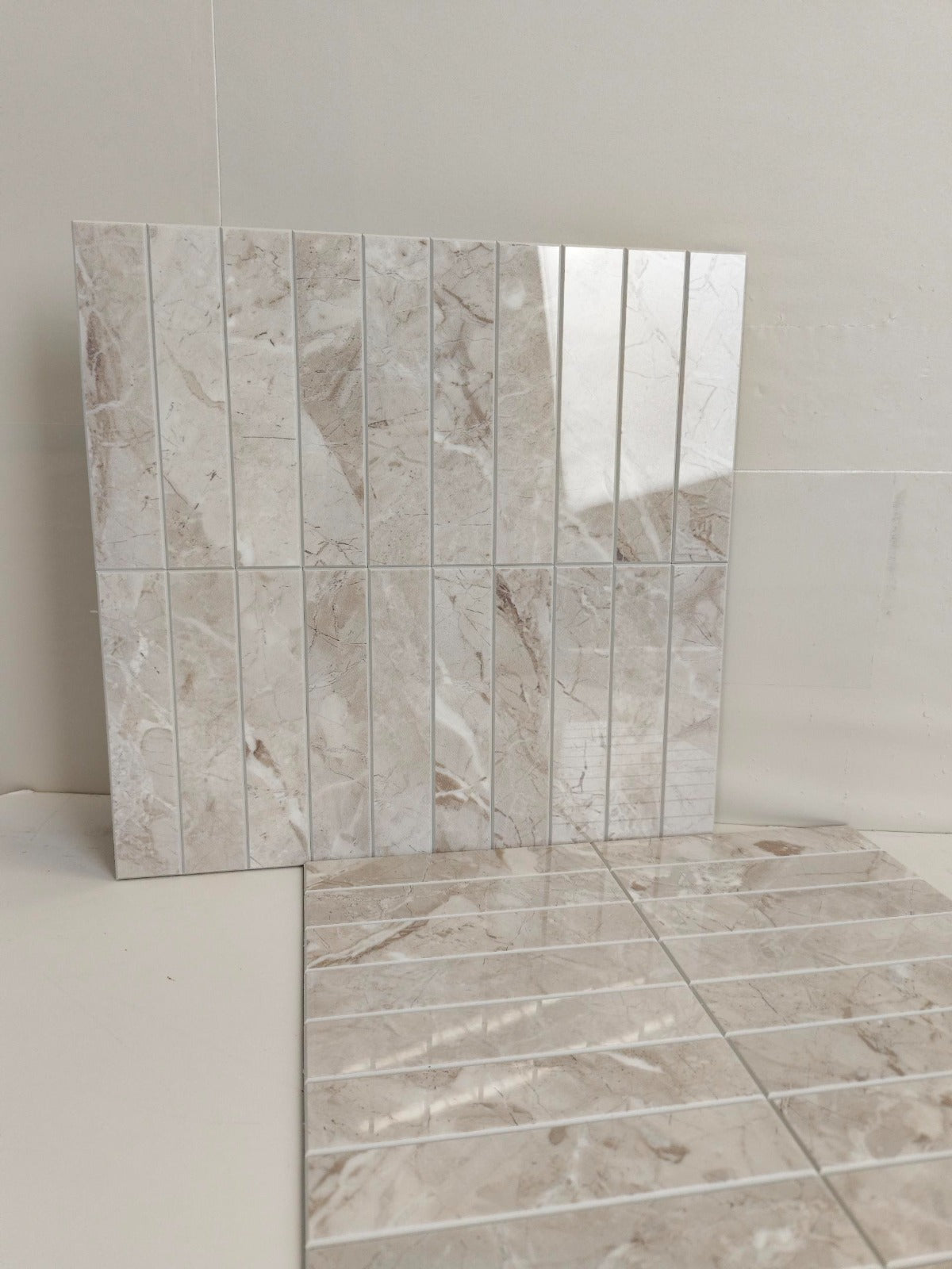 Tile sample with a beige and brown marble-like pattern on a white background