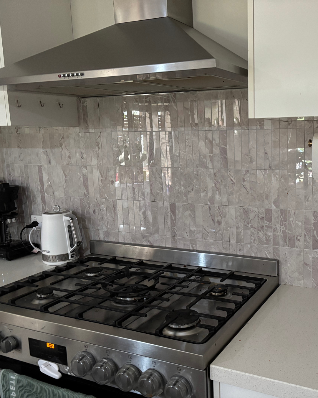 Stainless steel gas stove with tiled backsplash in a kitchen