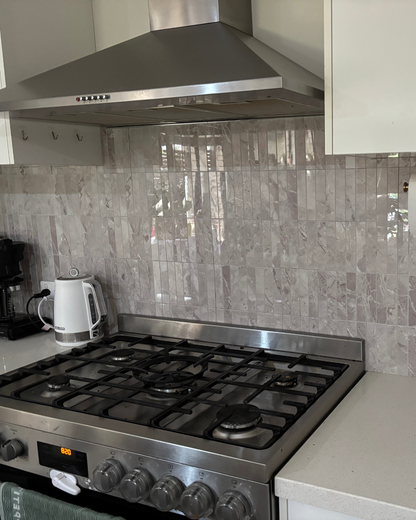 Stainless steel gas stove with tiled backsplash in a kitchen