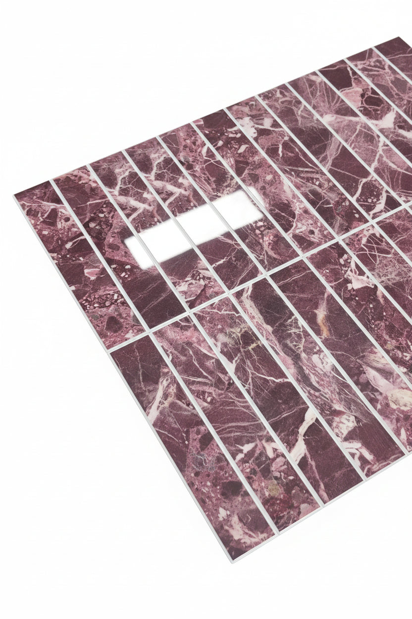 A rectangular sheet of marble-look tiles or tiles arranged in a grid, showing a pinkish-red and white veined pattern, photographed on a dark textured carpet.