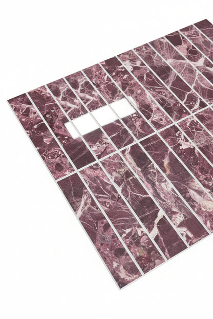 A rectangular sheet of marble-look tiles or tiles arranged in a grid, showing a pinkish-red and white veined pattern, photographed on a dark textured carpet.