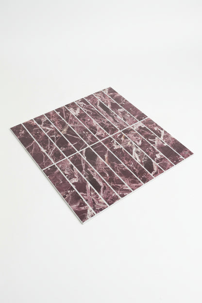 A sheet of rectangular marble-patterned tiles or decals with a pink, burgundy, and white veined design, laid diagonally on a dark gray textured carpet.