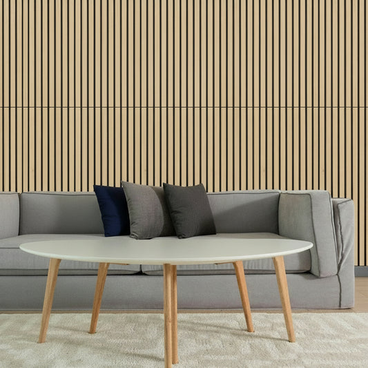 Gray sofa with colorful cushions and a white coffee table in front of a striped wall.