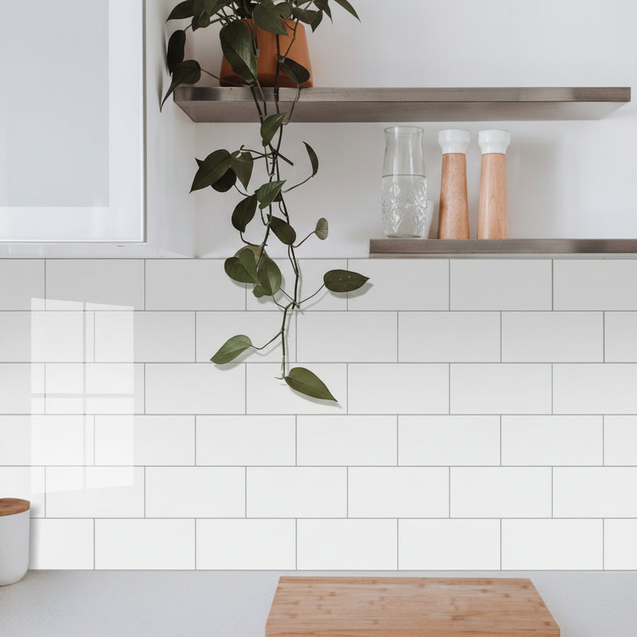 Kitchen with white tiled wall, wooden cutting board, and shelves with decor items.