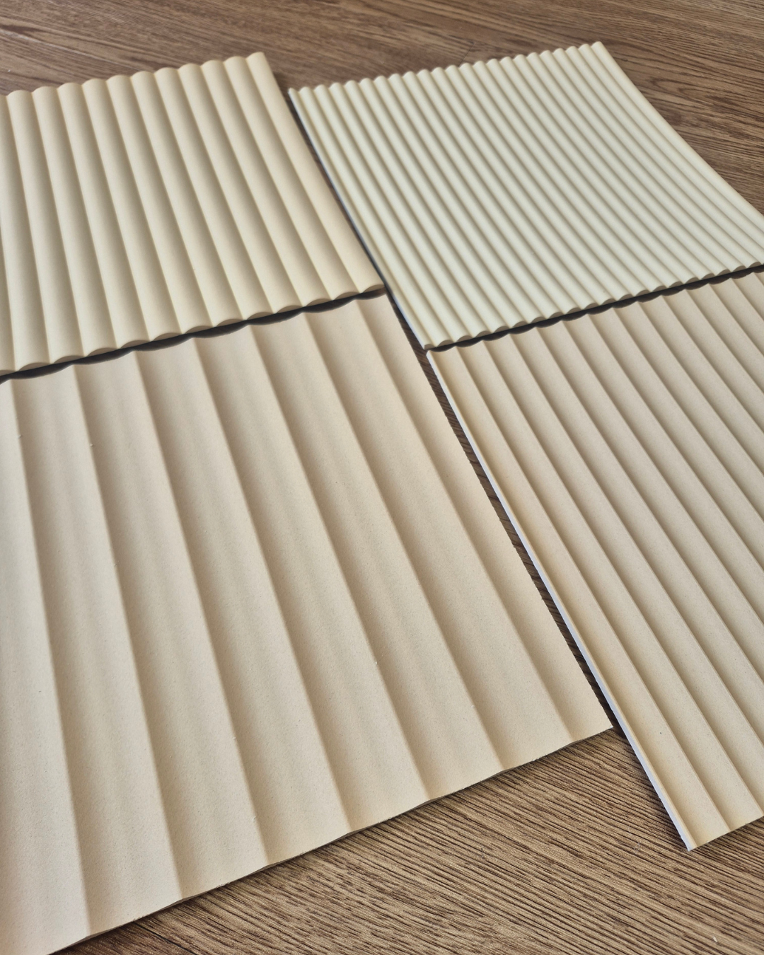 Two beige acoustic panels with ribbed texture on a wooden floor.